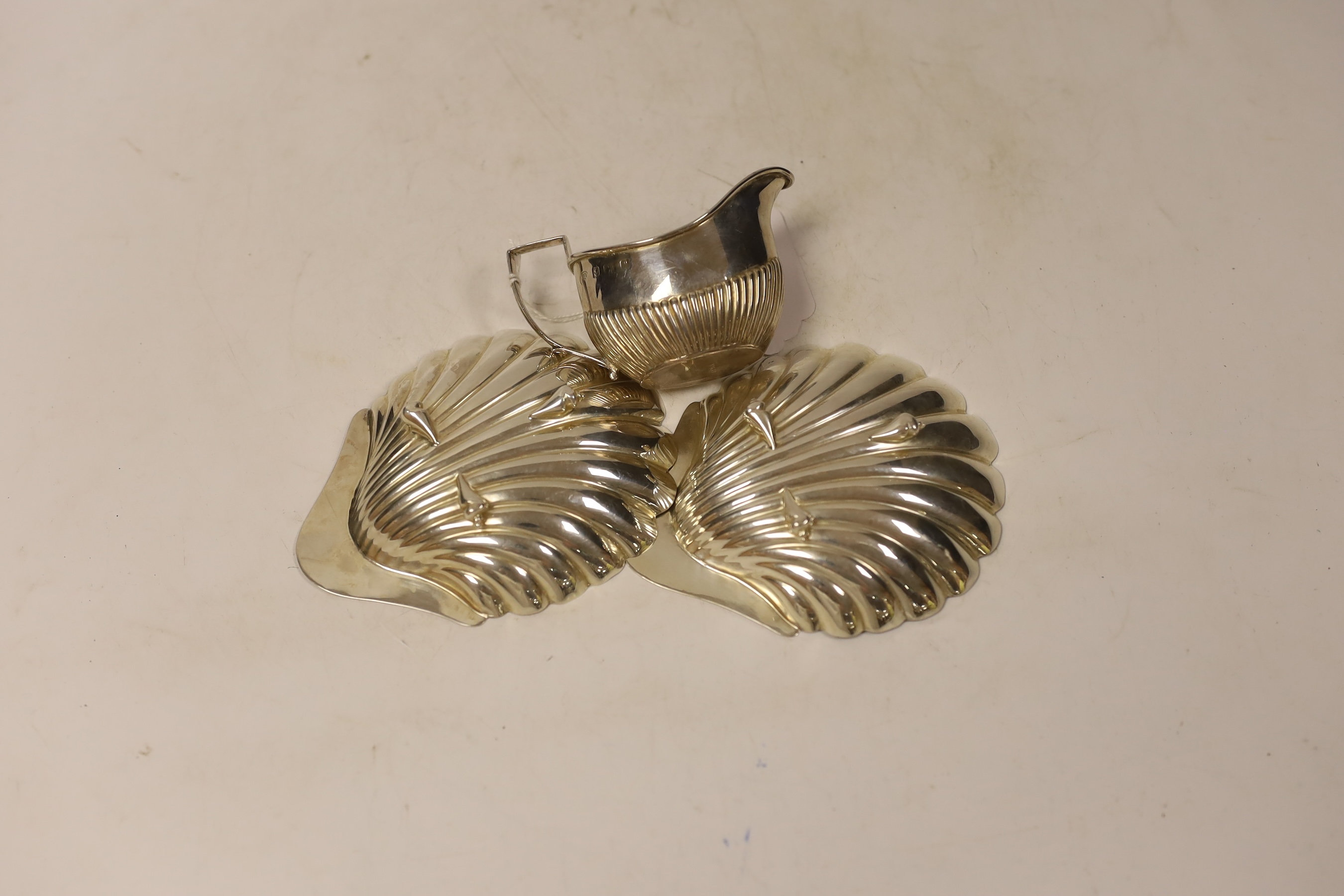 A pair of late Victorian silver scallop dishes, Atkin Brothers, Sheffield, 1890, 11.9cm and a small silver cream jug.